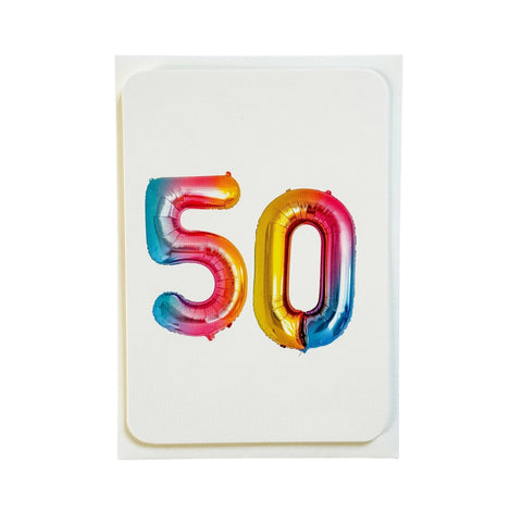 A white greeting card featuring the number '50' in metallic, foil-like balloons with a rainbow gradient of blue, pink, orange, and yellow, set against a plain white background.