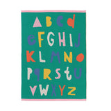 A square green alphabet blanket featuring colorful, playful capital letters from A to Z in pink, yellow, purple, orange, and white, with a pink border on a white background.