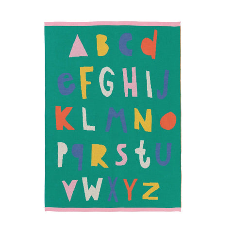 A square green alphabet blanket featuring colorful, playful capital letters from A to Z in pink, yellow, purple, orange, and white, with a pink border on a white background.