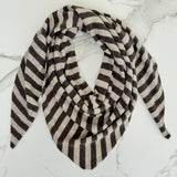 A triangular scarf with horizontal black and beige stripes, styled in a loop on a white marble surface.