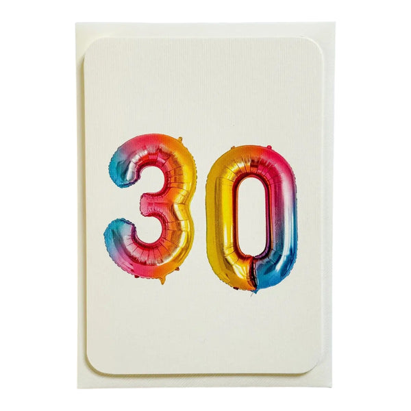 A square birthday card with a white envelope, featuring the number '30' in a metallic foil balloon in a a red, orange, yellow, and blue gradient.