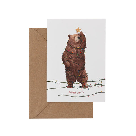Greeting card with a bear wrapped in lights and a star on its head, with a brown envelope.