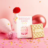 White chocolate and confetti birthday cake chocolate bar with a birthday hat and balloons on a pink background