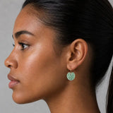 Close-up of a woman wearing a green leaf earring against a neutral background