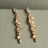 Gold earrings with clear stones on a green surface