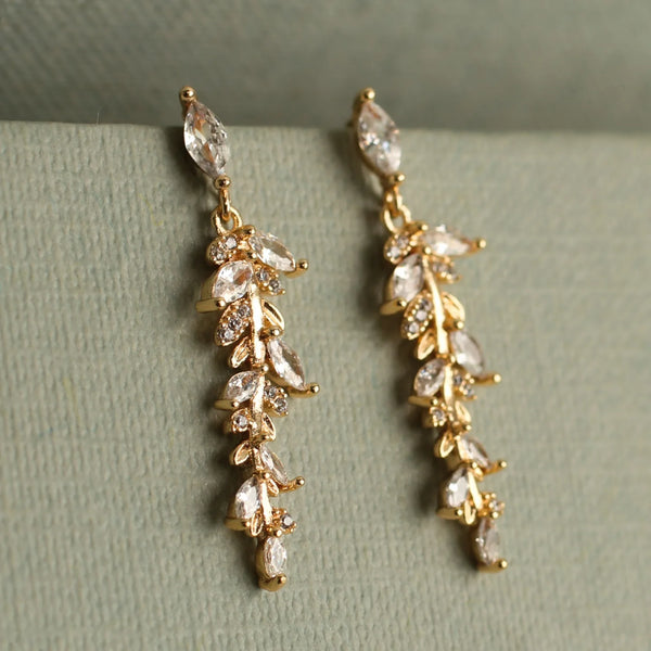 Gold earrings with clear stones on a green surface