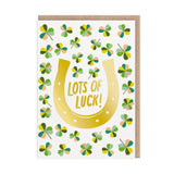Greeting card with a gold horseshoe and four-leaf clover pattern, featuring the text 'Lots of Luck!'.