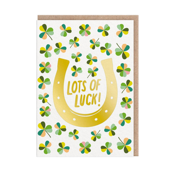 Greeting card with a gold horseshoe and four-leaf clover pattern, featuring the text 'Lots of Luck!'.