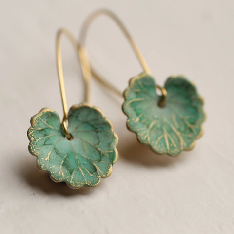 Pair of green leaf-shaped earrings on a light gray background