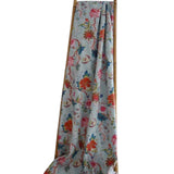 Floral patterned fabric draped over a wooden rod on a white background