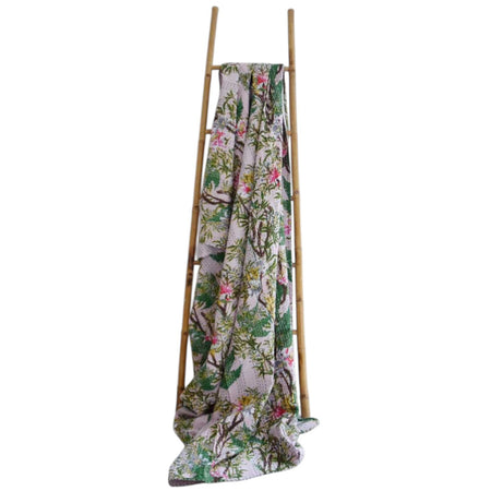 Floral-patterned blanket draped over a wooden ladder on a white background