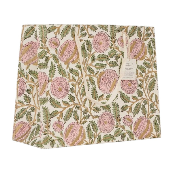 A square fabric gift bag featuring a vintage floral pattern with pink flowers and green leaves on an off-white background. A small paper brand tag is attached to the right side.