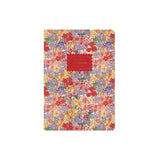 A floral notebook with a dense multicolor pattern of red, yellow, purple, and green flowers on a light background, featuring a red rectangular label in the center with gold text.
