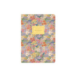 A floral patterned notebook with a yellow label reading 'Notebook' on a plain white background.