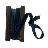 Spool of dark blue ribbon on a wooden reel with a single strip draped over it, on a white background.