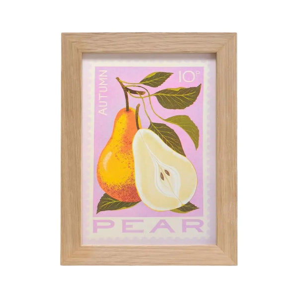 A framed art print featuring an autumn pear illustration with a whole and halved pear on a light pink background, enclosed in a natural wood frame.
