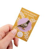 Pigeon enamel pin badge on a yellow card held by a hand