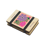 Small flower press with floral design and black elastic band on a white background