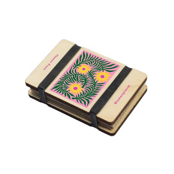 Small flower press with floral design and black elastic band on a white background