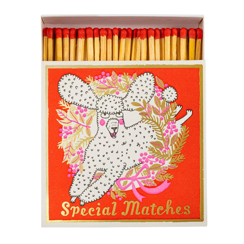 Matches box with a decorative label illustrated with a white curly poodle circled by a golden wreath with pink bows. All on a red background with the words Special Matches in gold.