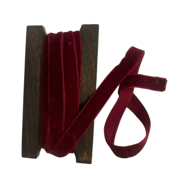 Spool of red velvet ribbon on a white background