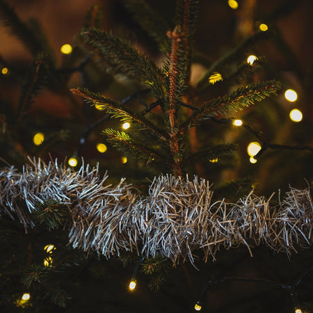 Decorated Christmas tree with lights and tinsel against a dark background