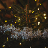 Decorated Christmas tree with lights and tinsel against a dark background