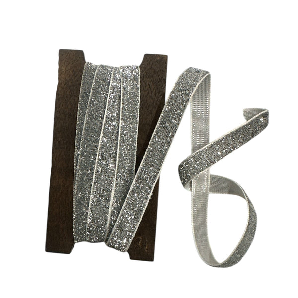 Silver glitter ribbon on a wooden spool on a white background