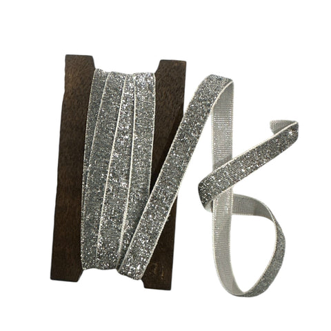 Silver glitter ribbon on a wooden spool on a white background