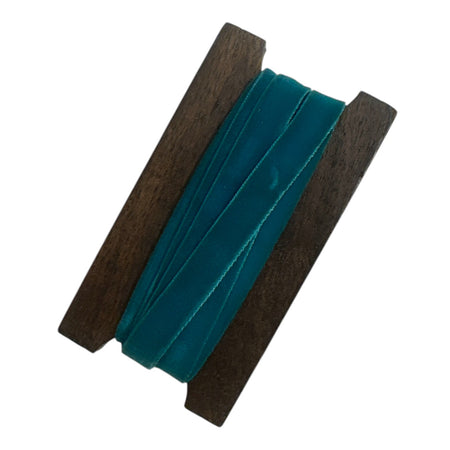 Teal ribbon with wooden reel on a white background