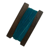 Teal ribbon with wooden reel on a white background