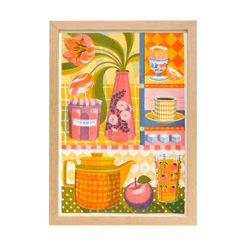 A framed print showing a brightly coloured teapot, vase of tulips, cup and saucer and a eggcup