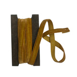 Spool of mustard velvet ribbon on a white background