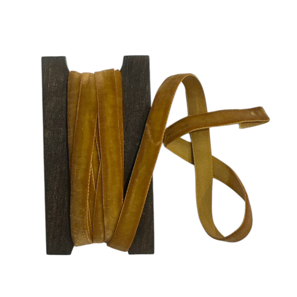 Spool of mustard velvet ribbon on a white background