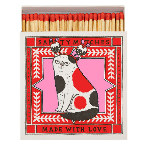 Matches box with a white red and black spotty cat wearing a Christmas pudding headband with the text Safety Matches Made with Love on a pink and red patterned background.