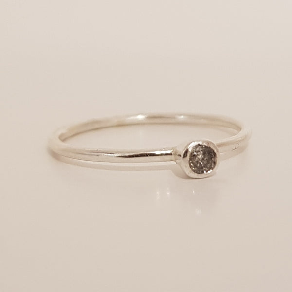 This salt and pepper diamond ring is encased in a silver mount that protrudes from the ring band.