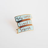Shing gold and pastel blue pin brooch with the text 'Self Care Isn't Selfish'