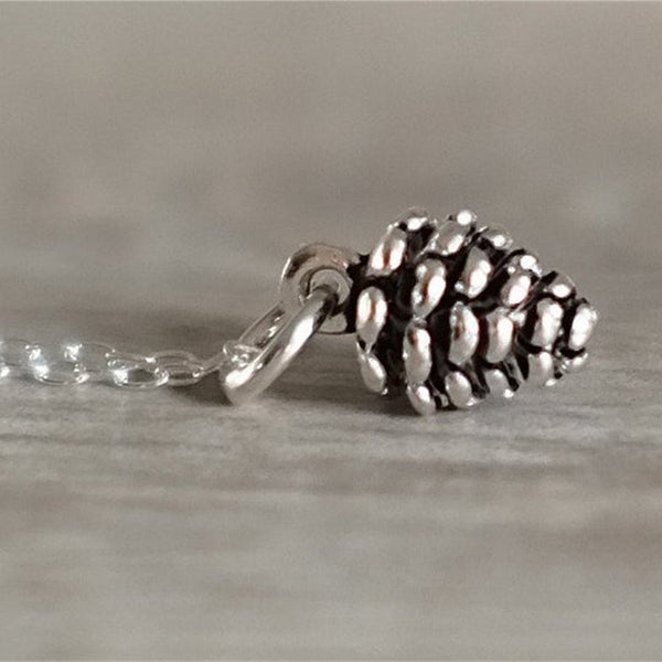 Silver pine cone charm on a silver necklace.